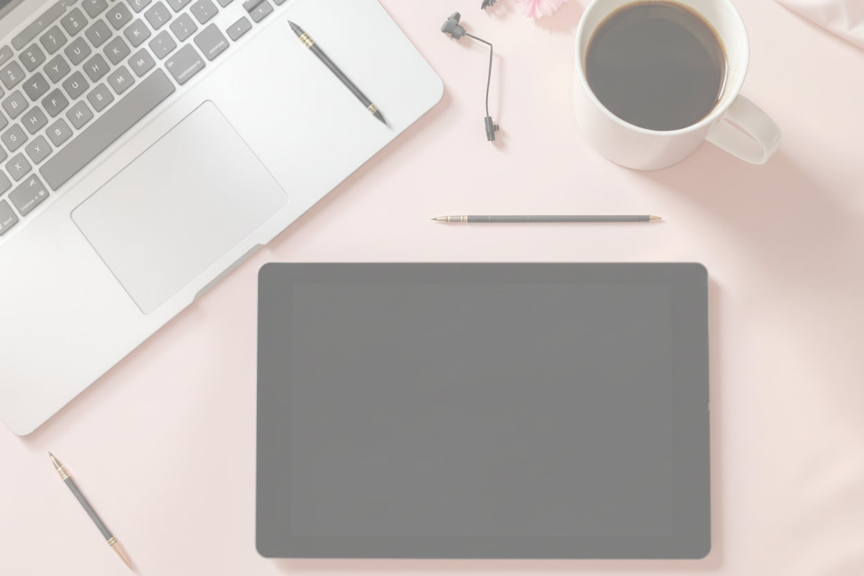 Laptop, tablet, coffee cup, and stationery on a pink surface