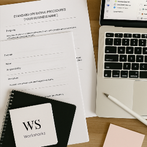 Laptop, notebook, and documents on a desk with 'WS Worksharks' branding.